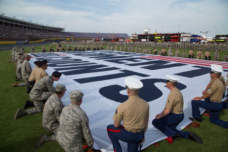 Service members unfurl a section of the USO’s Every Moment Counts flag before the start of the Coca-Cola 600 in Charlotte, North Carolina, in May. USO photo by Joseph Andrew Lee